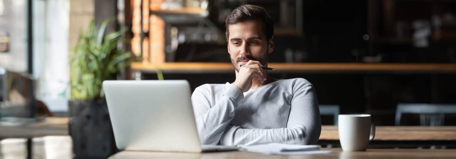 Male student looking at laptop with satisfied look on his face.