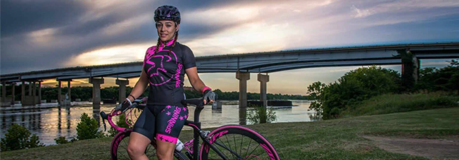 Cyclist stands with bike in front of a body of water