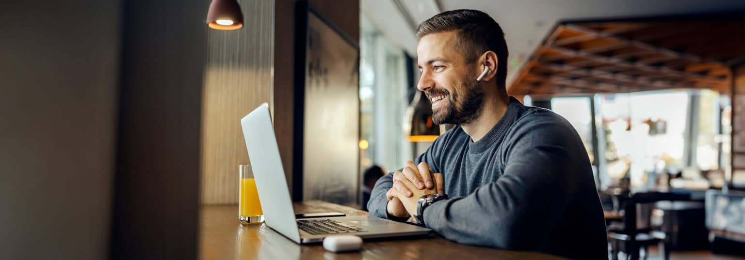 Smiling man looking at a laptop.