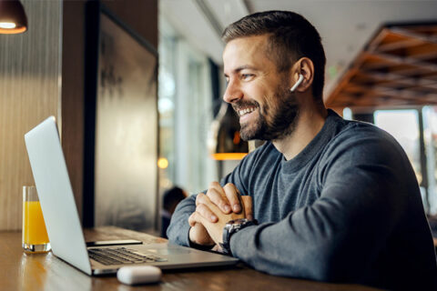 Smiling man looking at a laptop.