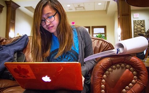 student working on laptop in library