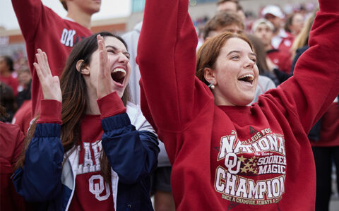 students wearing OU gear cheering at a football game