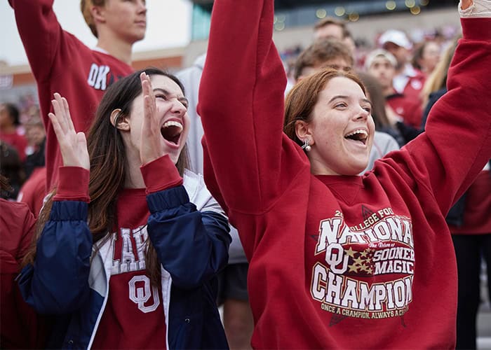 students wearing OU gear cheering at a football game