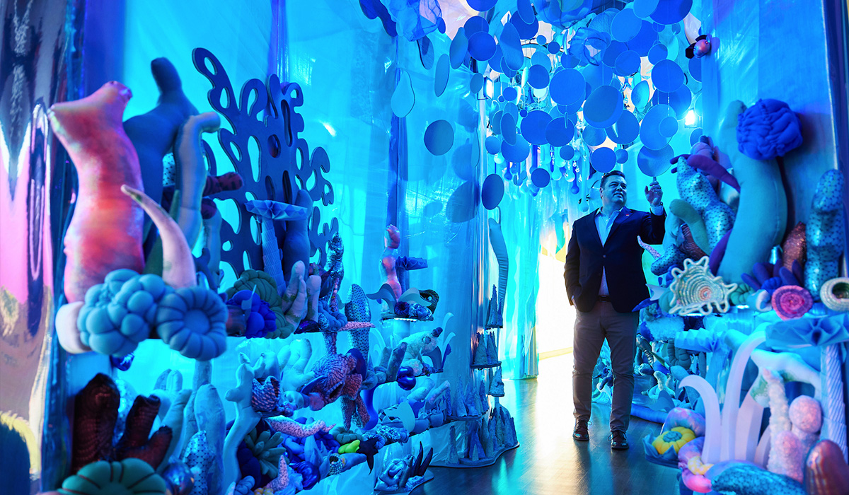 A man standing in front of a tunnel-like art display, exuding a sense of curiosity and anticipation.