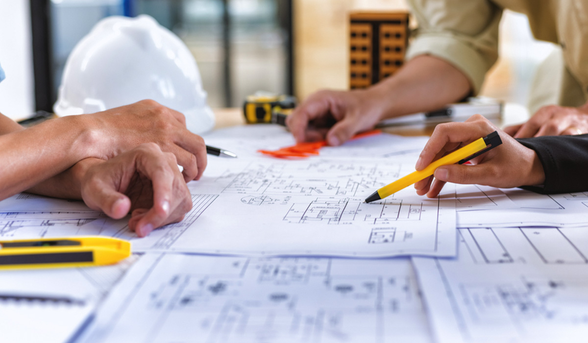 image showing hands of 3 people working on site plans