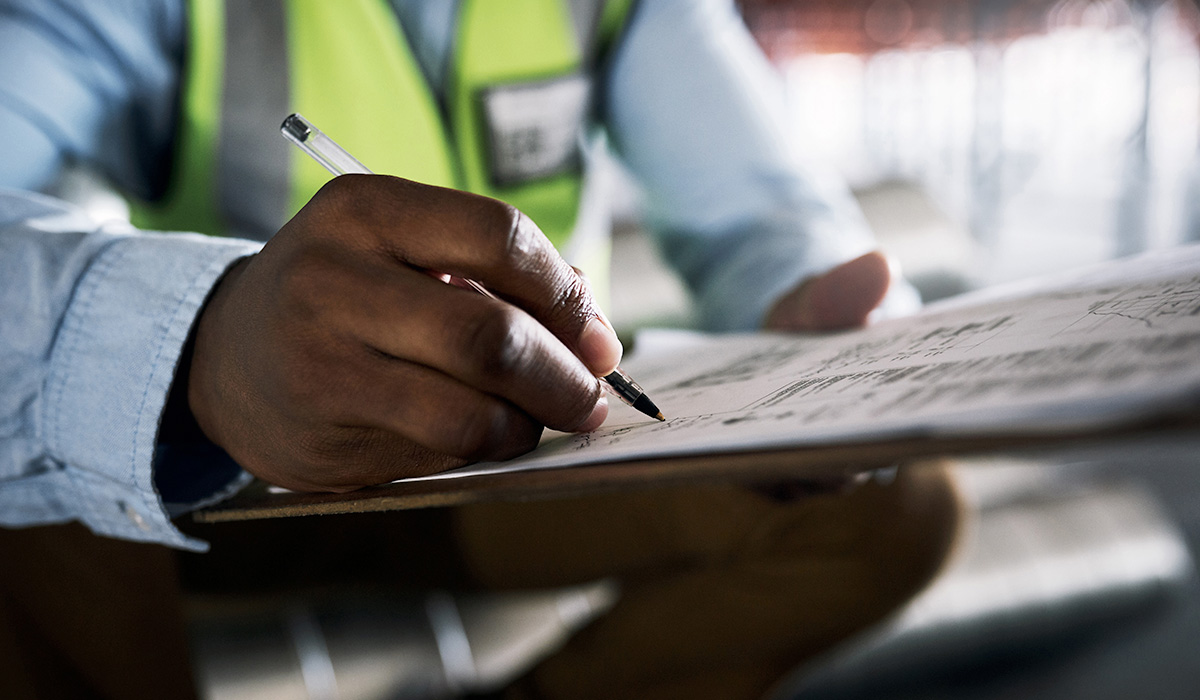 close up of construction manager's hand taking notes on site plans