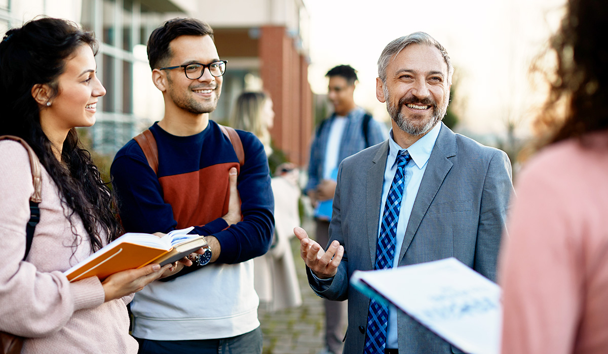 education administer talking to teachers in front of a building