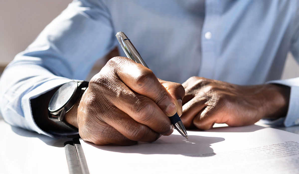 close up of hands on a notebook with a pen in one hand