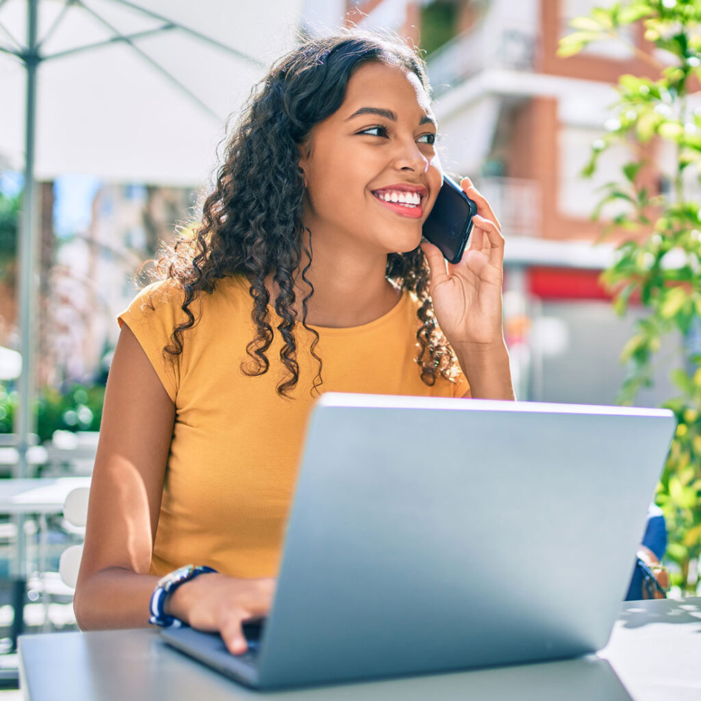 smiling student using her laptop and phone