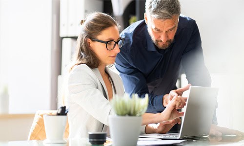 decorative image of energy business executives at a desk discussing project that is on the laptop