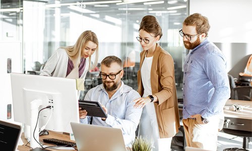 decorative image coworkers gathered at a desk viewing a tablet