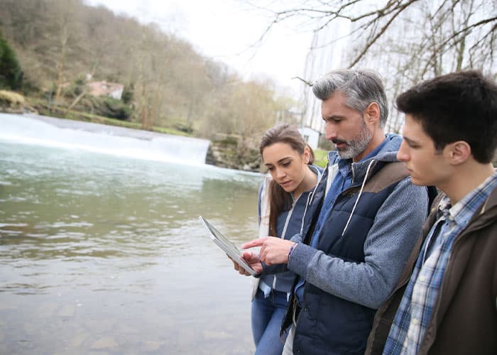 decorative image of professor with two students view water data on tablet