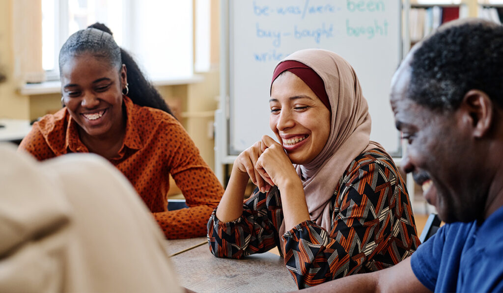 3 smiling students sitting around a table