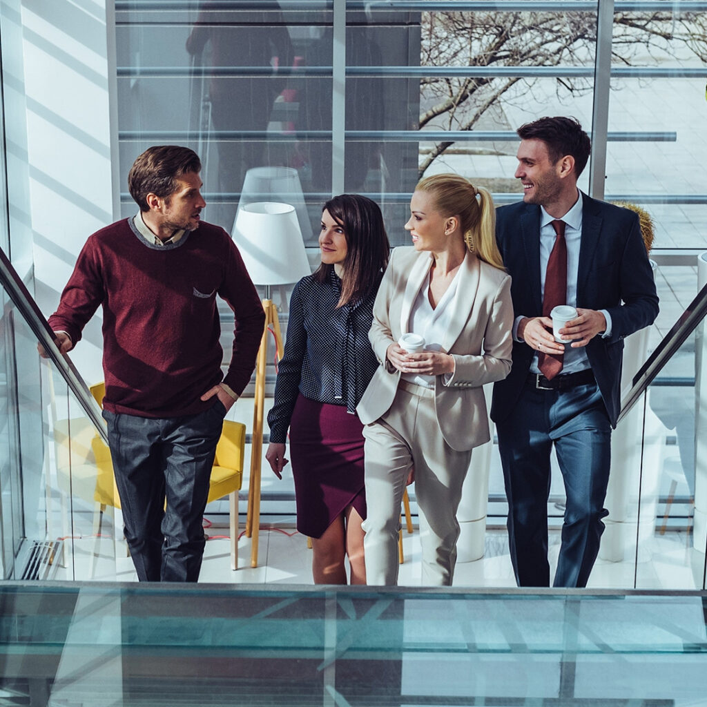 group of 4 students in business attire walking up a stairway