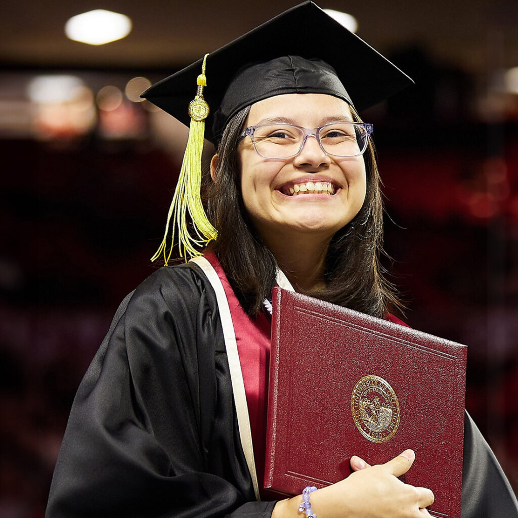 Smiling student at graduation holding her diploma cover