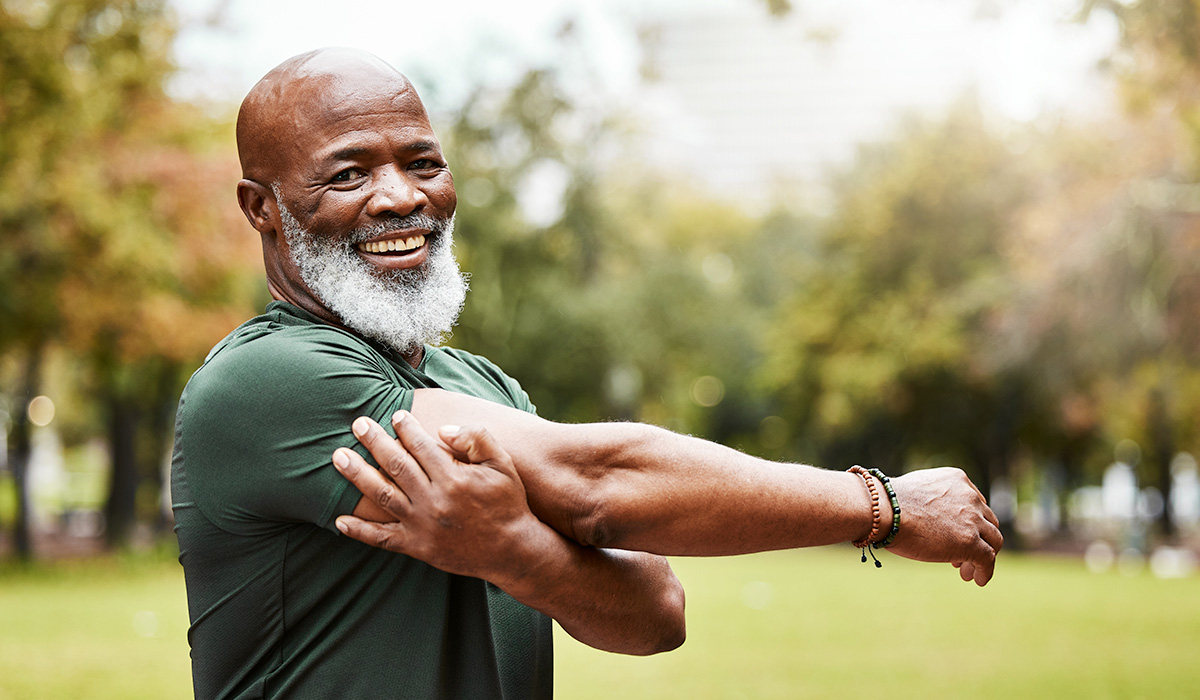 decorative image of a smiling man doing arm stretches in a park