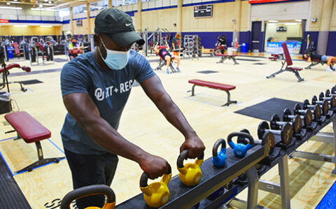 Student picking up hand weights at Sarkey's Fitness Center