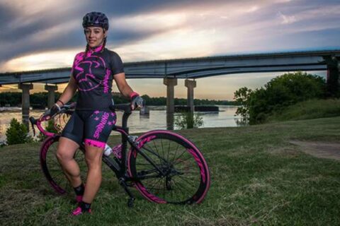 Cyclist stands with bike in front of a body of water