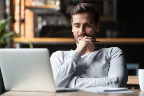 Male student looking at laptop with satisfied look on his face.