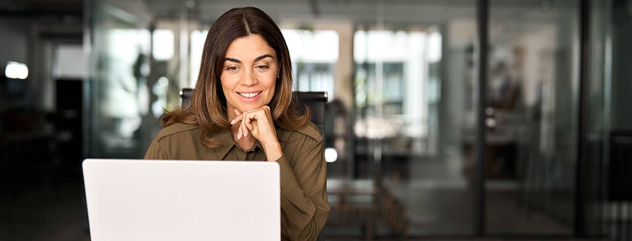 Smiling student sitting at her desk and looking at her laptop