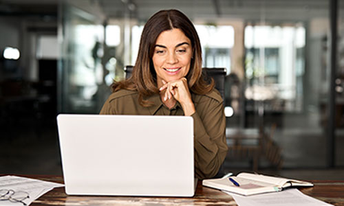 Smiling student sitting at her desk and looking at her laptop