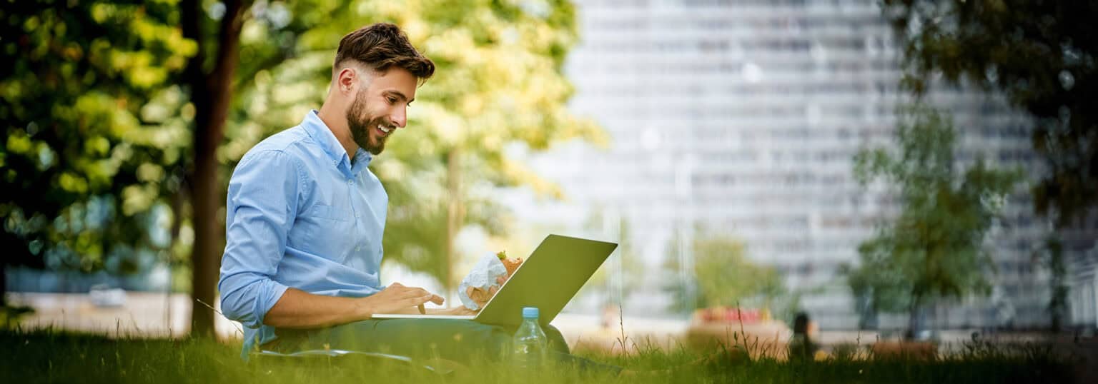 A man working on a laptop in a pleasant outdoors setting.