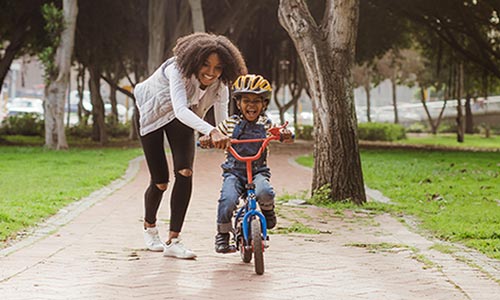 Smiling mother teaching her son to ride a bike