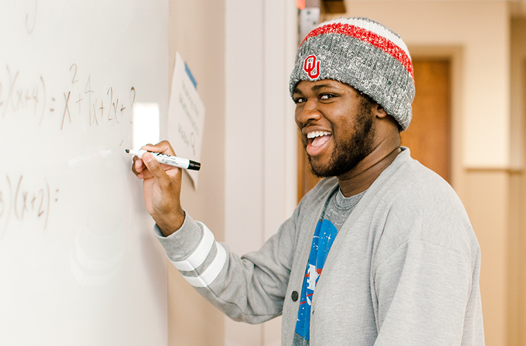 OU College of Education students leading a math class and writing math problems on a white board
