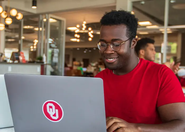 Person in red shirt sitting with laptop