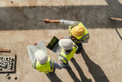 Group of people in hard hats discussing over laptop