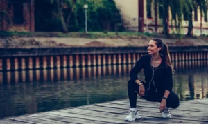woman sitting on a wooden pathway putting on her running shoes