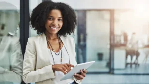 Smiling cybersecurity leaders leaning against a glass wall while holding a tablet