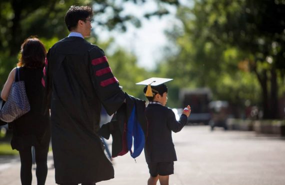graduating student walking on the south oval with his son